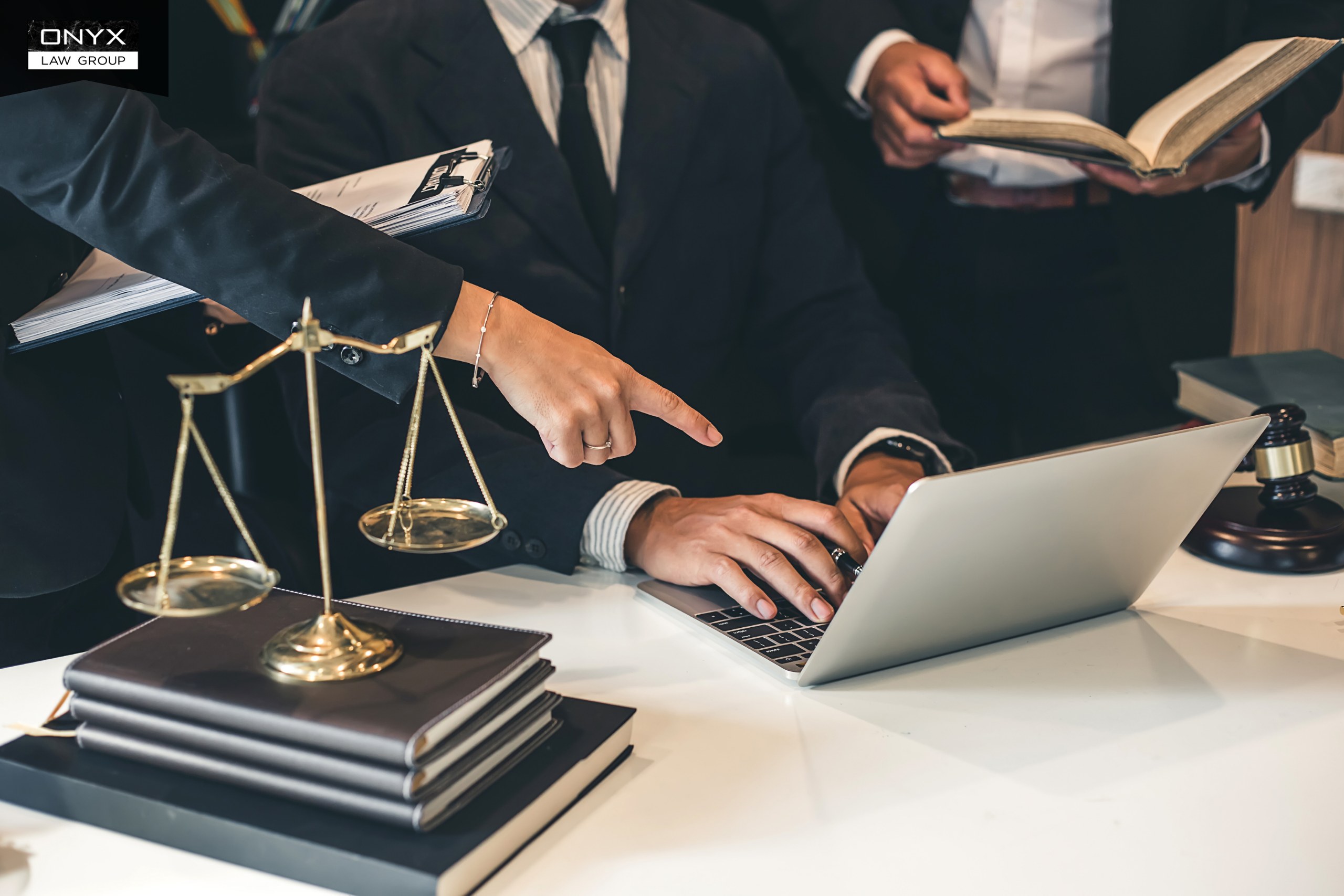 Talking to a Lawyer About Your Will Lawyers reviewing documents together at a desk with a laptop, law books, a gavel and scales of justice, with the Onyx Law Group logo
